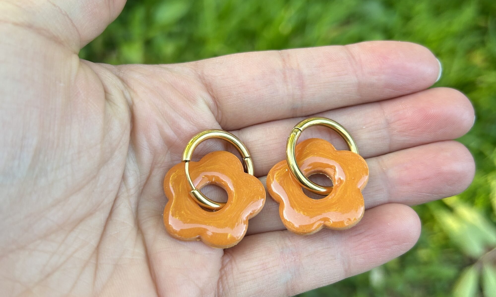 pampilles couleur cognac présenté dans une main avec des créoles