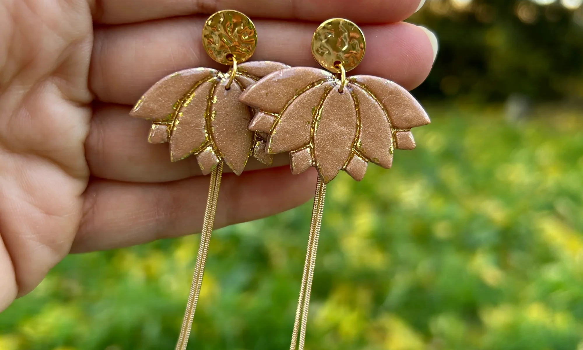Présentation boucles d'oreilles en forme de fleur de lotus de couleur beige avec de la dorure
