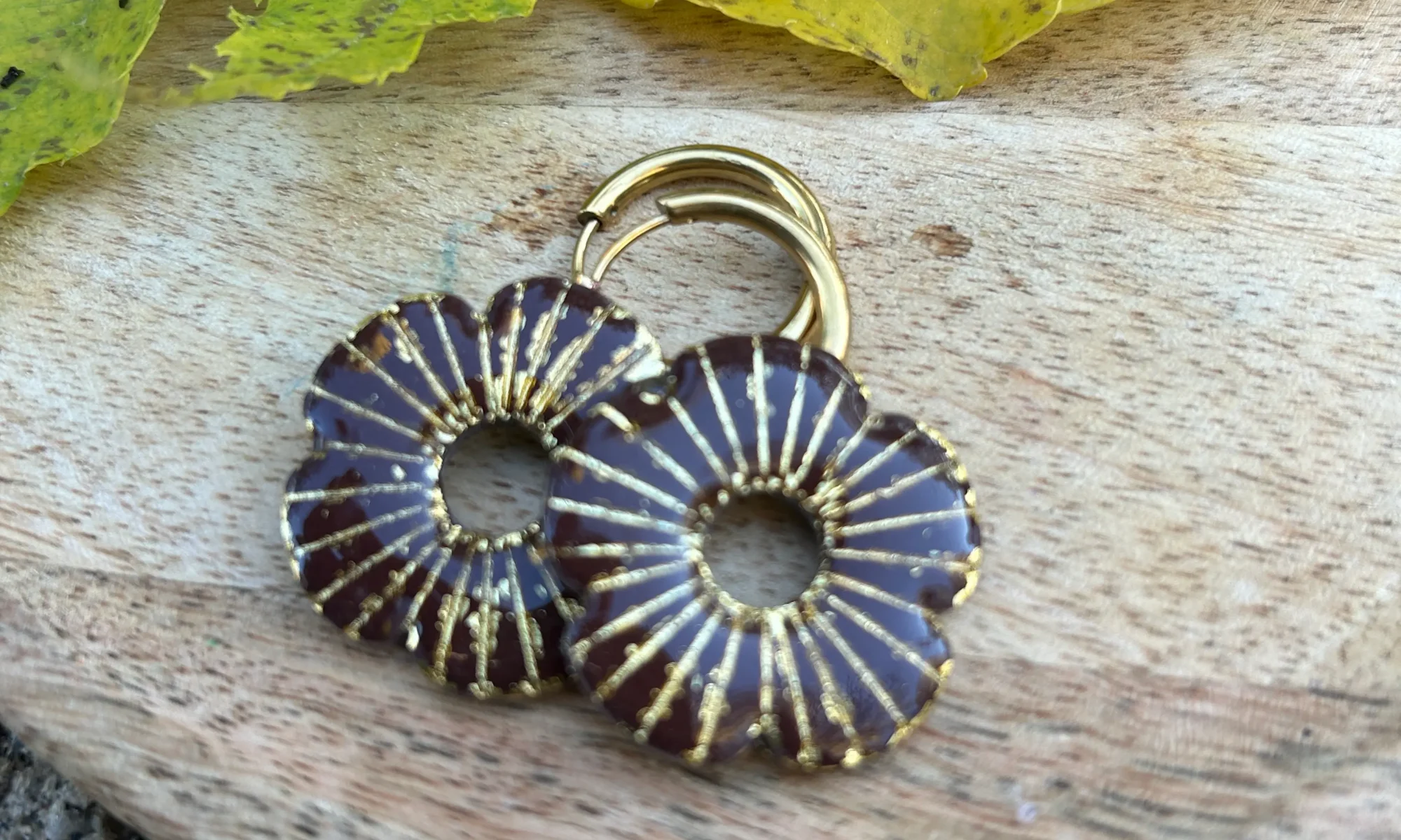 présentation de bijoux pour créoles interchangeables en forme de coquelicot et couleur marron sur un plateau