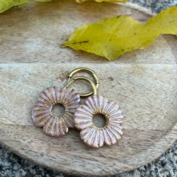 présentation de bijou sur un plateau avec une décoration feuille. Pampilles pour créoles, forme coquelicot, beige et doré