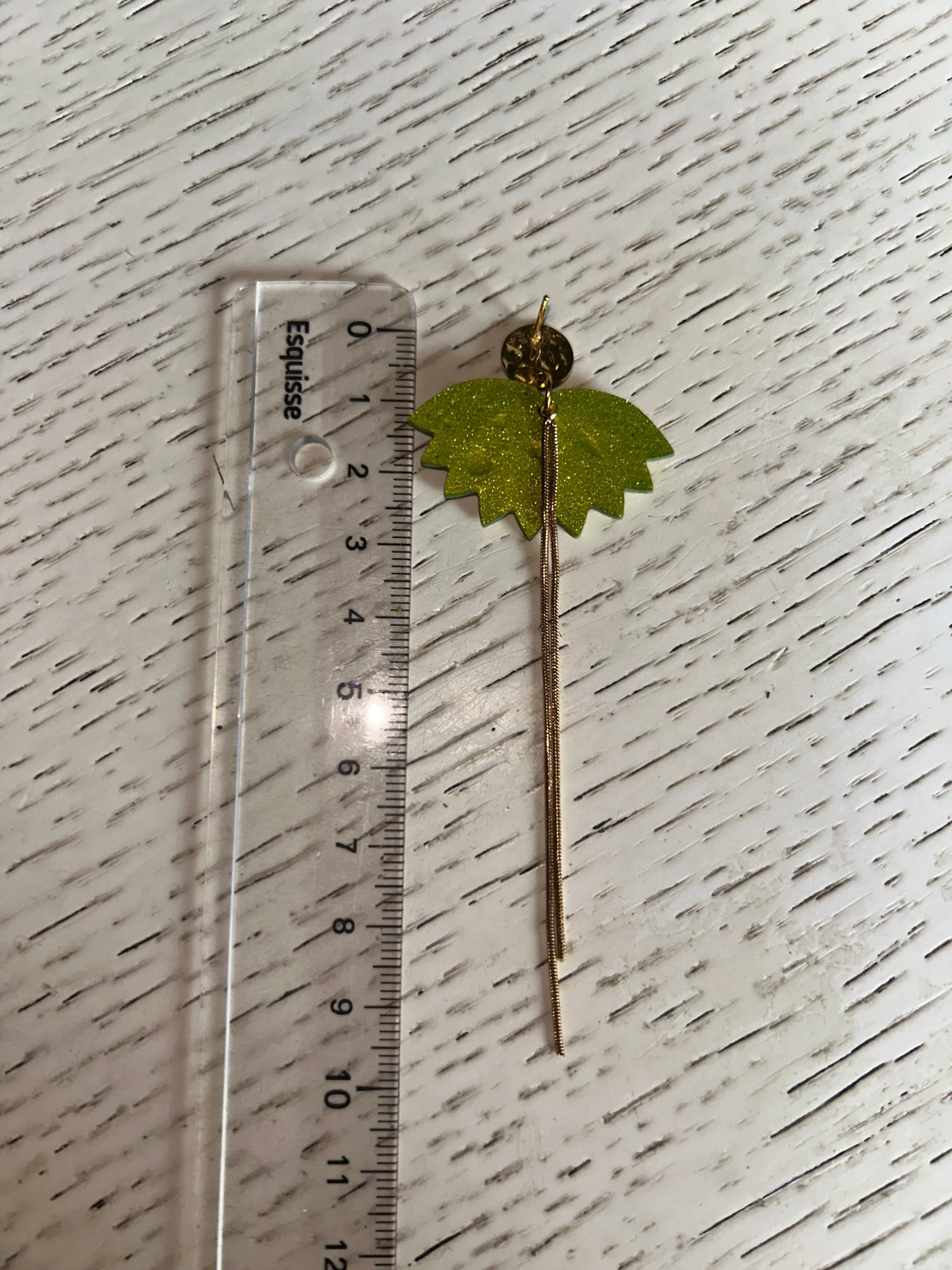 photo montrant la longueur de la boucles d'oreilles avec une regle posé à coté
